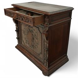 19th-century heavily carved oak baroque style cupboard with vine and floral carved frieze drawer above panelled cupboard door with floral carved appliqué (detached) flanked by symmetrically carved scroll and vine decorated sides, on bun feet 