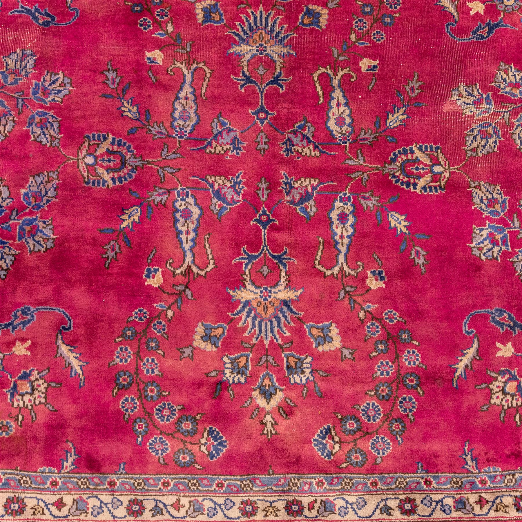 Large Persian-style mahal-type hand-knotted carpet, of rectangular form with a deep crimson field decorated with an all-over arrangement of stylized floral sprays and palmettes, with a central subtle medallion composition enclosed by a dark navy main border of scrolling floral motifs between narrow guard stripes with fringe ends 