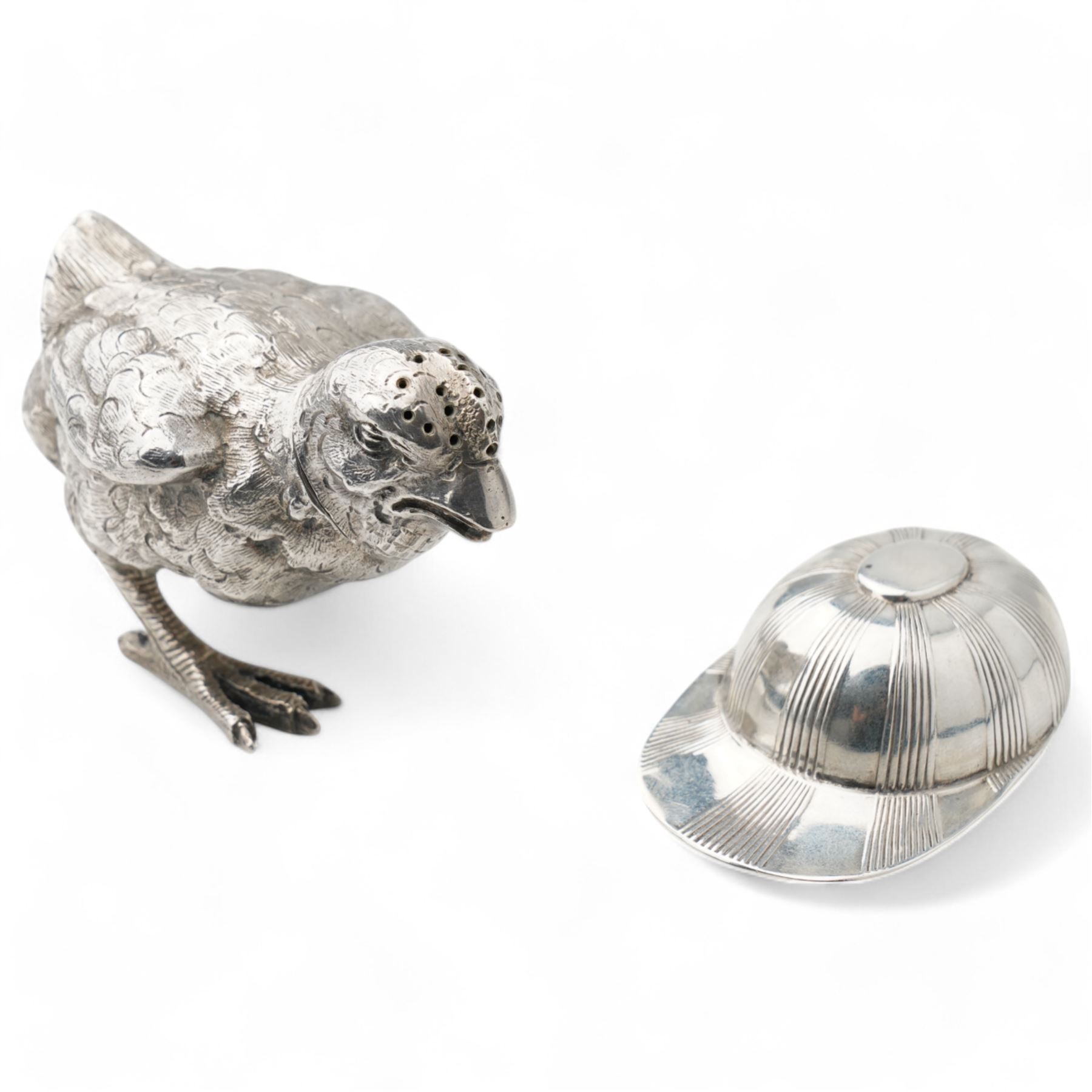  German silver novelty pepper pot in the form of a running chick, realistically modelled L8cm London 1922 Maker Berthold Hermann Muller and a silver jockeys cap caddy spoon Sheffield 1954 Maker Atkin Bros (2)