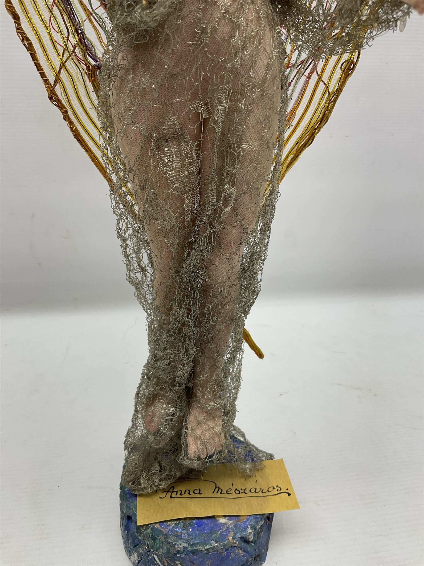 Anna Meszaros Hungary - hand made needlework figurine of an Angel with metallic lace full length dress and open threadwork wings; on moulded base H45cm Auctioneer's Note: Anna Meszaros came to England from her native Hungary in 1959 to marry an English businessman she met while demonstrating her art at the 1958 Brussels Exhibition. Shortly before she left for England she was awarded the title of Folk Artist Master by the Hungarian Government. Anna was a gifted painter of mainly portraits and sculptress before starting to make her figurines which are completely hand made and unique, each with a character and expression of its own. The hands, feet and face are sculptured by layering the material and pulling the features into place with needle and thread. She died in Hull in 1998.