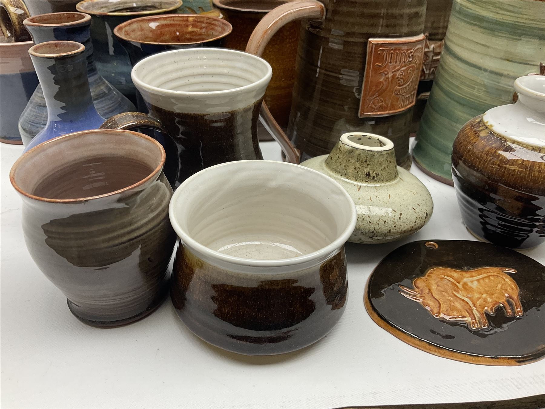 Wold studio pottery tankards, in various colours and relief decoration together with other studio items including vases, jugs and pots 