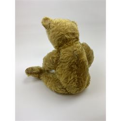 Early 20th century German teddy bear c1920, probably Steiff or Bing, with wood wool filled humped back golden mohair body, swivel jointed head with glass eyes and brown vertically stitched nose and mouth, jointed limbs with elongated arms and felt paw pads with black stitched claws H18