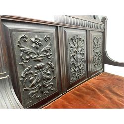 Late 19th century oak settle bench, shaped cresting rail carved with ribbon over triple panelled back, the panels relief carved with scrolled and floral urns and cartouche, hinged box seat, turned front feet, with upholstered squab cushion