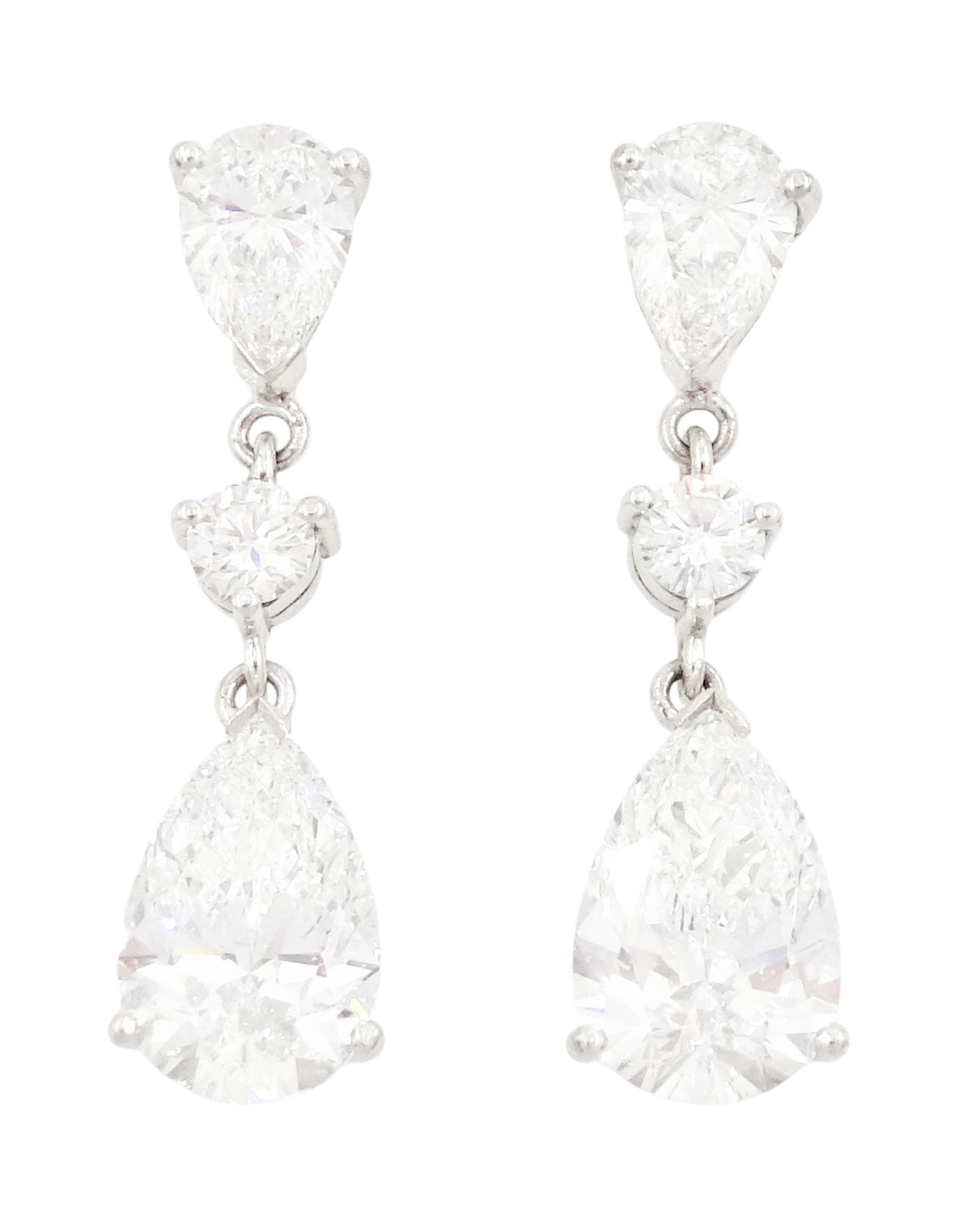 Pair of platinum diamond pendant earrings, each stud set with two pear cut diamonds, of 1.01 carat, 1.02 carat, 0.30 carat and 0.32 carat, spaced by a round brilliant cut diamond, total diamond weight 2.65 carat, each pear cut with a GIA certificate