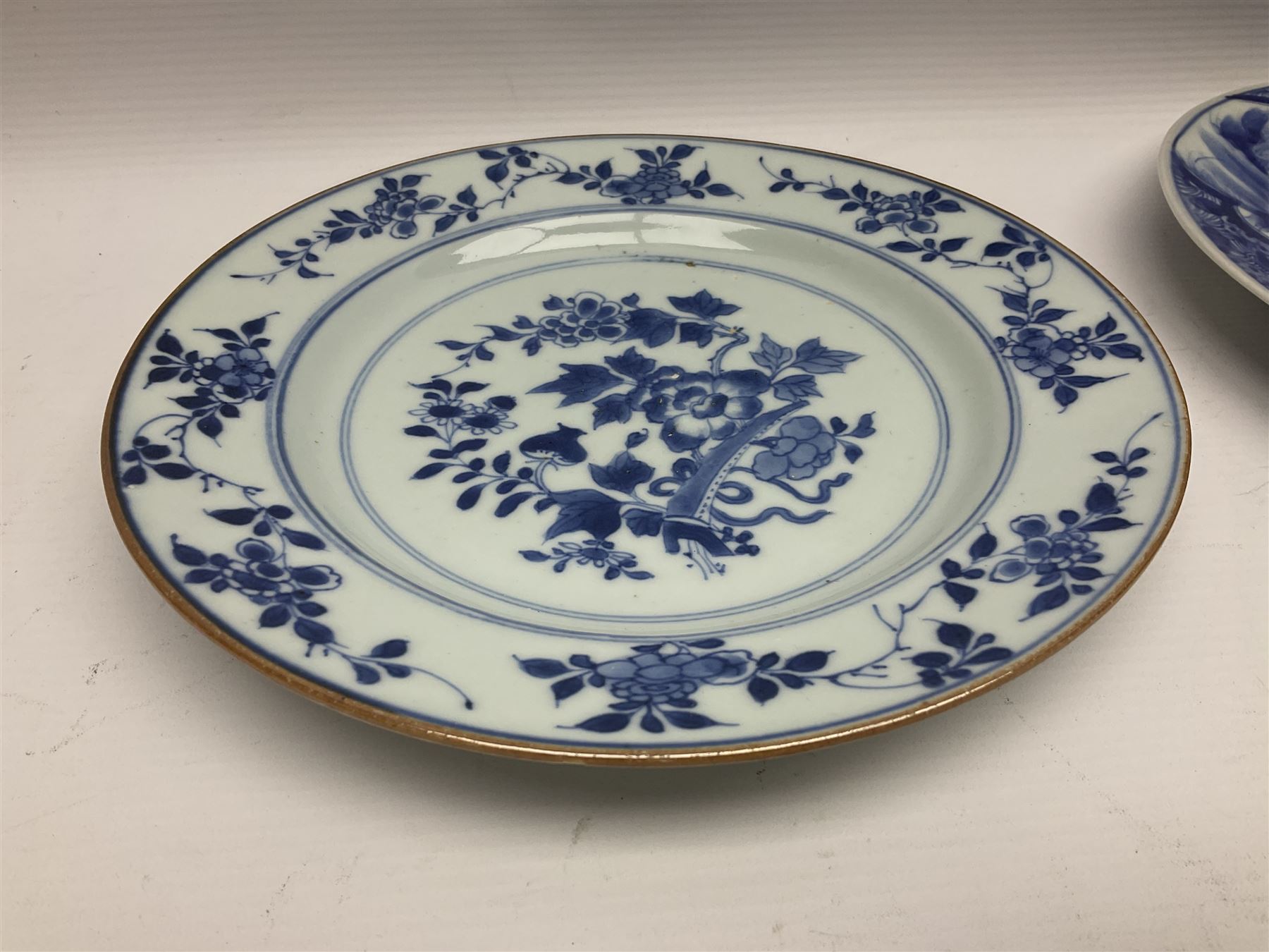 Japanese Meiji period Arita blue and white plate, of circular form, painted with riverside landscape and bird upon flowering branch, with character mark beneath, D24.5cm, together with two 18th century Chinese blue and white plates, each painted with floral design, each approximately D22.5cm
