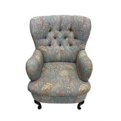 Mid-20th century wingback armchair, upholstered in soft blue floral patterned fabric with button-tufted backrest and curved arms and raised on cabriole supports