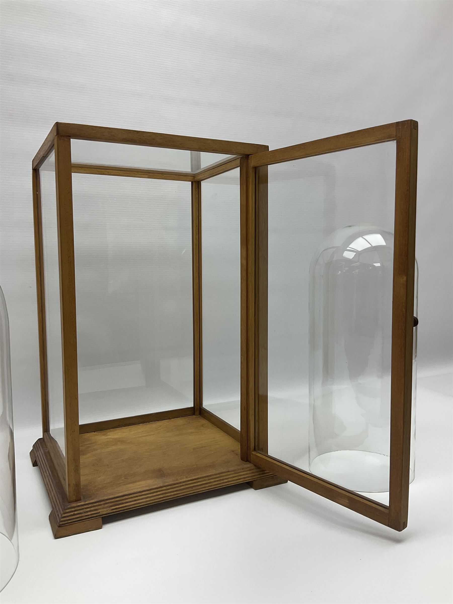 Tabletop glass display cabinet, with hinged door, together with two glass domes