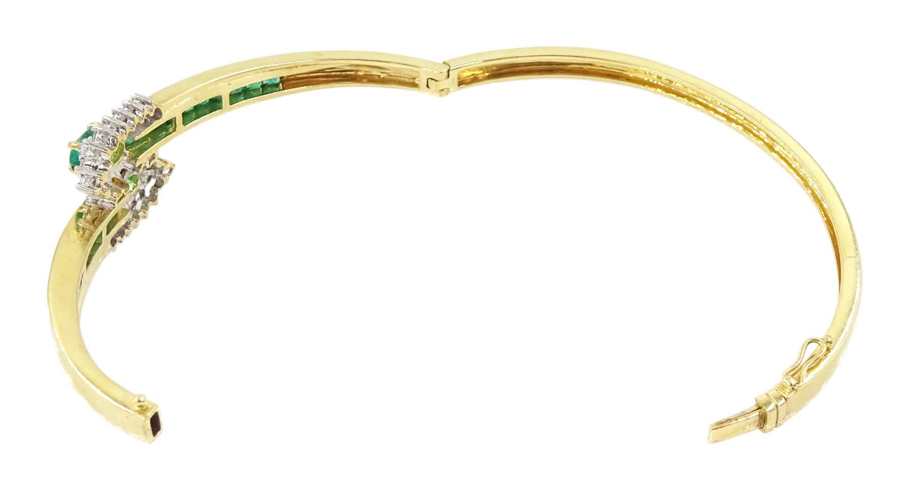 14ct gold emerald and diamond crossover bangle, two oval cut emeralds with round brilliant cut diamond surround, with channel set calibre cut emerald shoulders, stamped 585