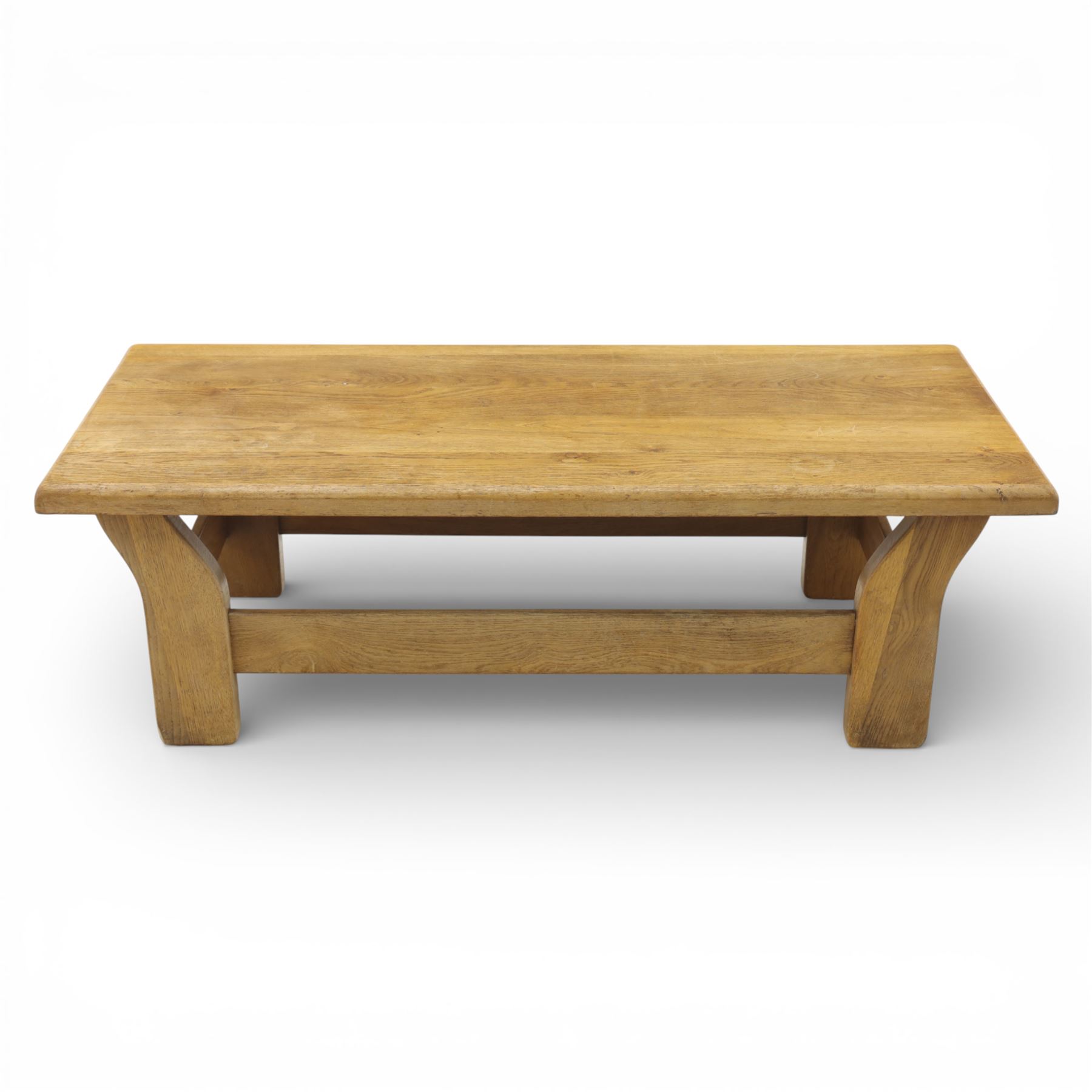 Modern oak coffee table, rectangular solid top with softly rounded edges, raised on shaped slab end supports united by a full-width stretcher