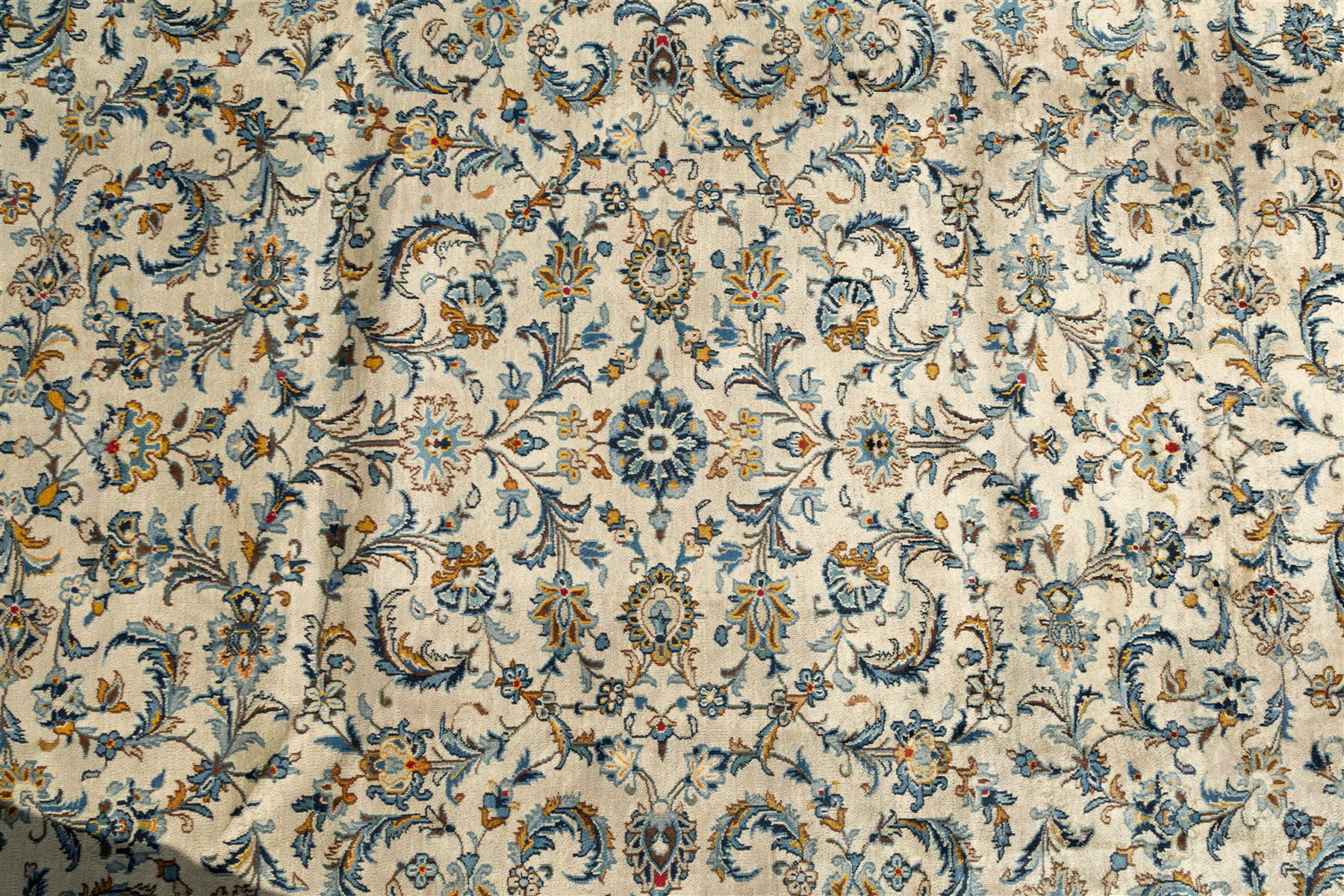 Central Persian Kashan hand-knotted carpet, ivory field profusely decorated with an all-over scrolling vine, palmette, and lotus design in shades of soft blue, pale gold, and green within floral borders