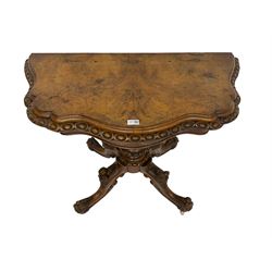 Victorian walnut serpentine card table, the stepped hinged and swivel top with moulded and egg and dart edges, figured frieze, turned pedestal on four splayed supports carved with fruit and berries, on ceramic castors