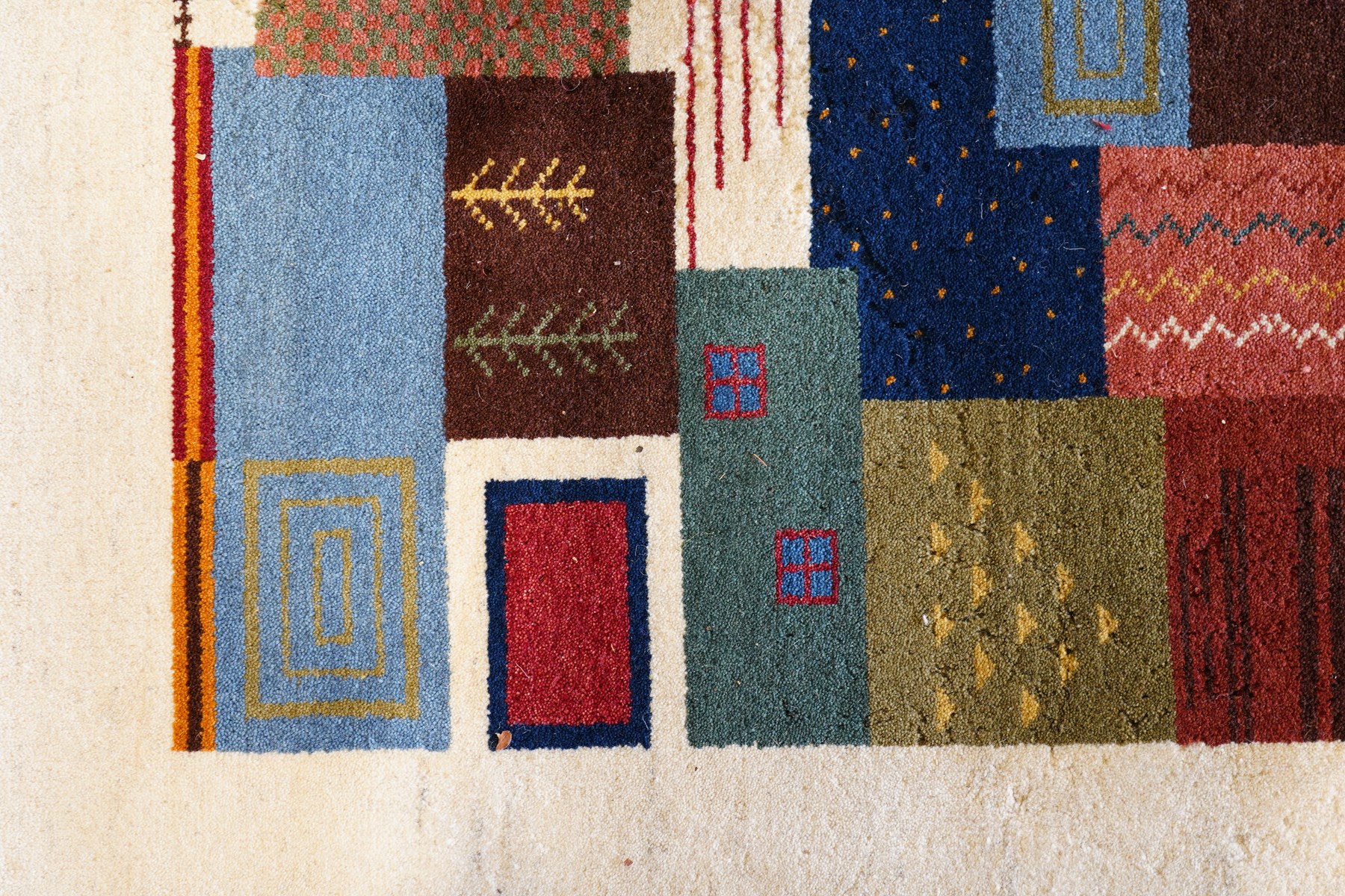 Persian style Gabbeh Loribaft design ivory ground rug, the vibrant field decorated with geometric patchwork design panels with interspersed stylised tree motifs, enclosed by a wide ivory guard band