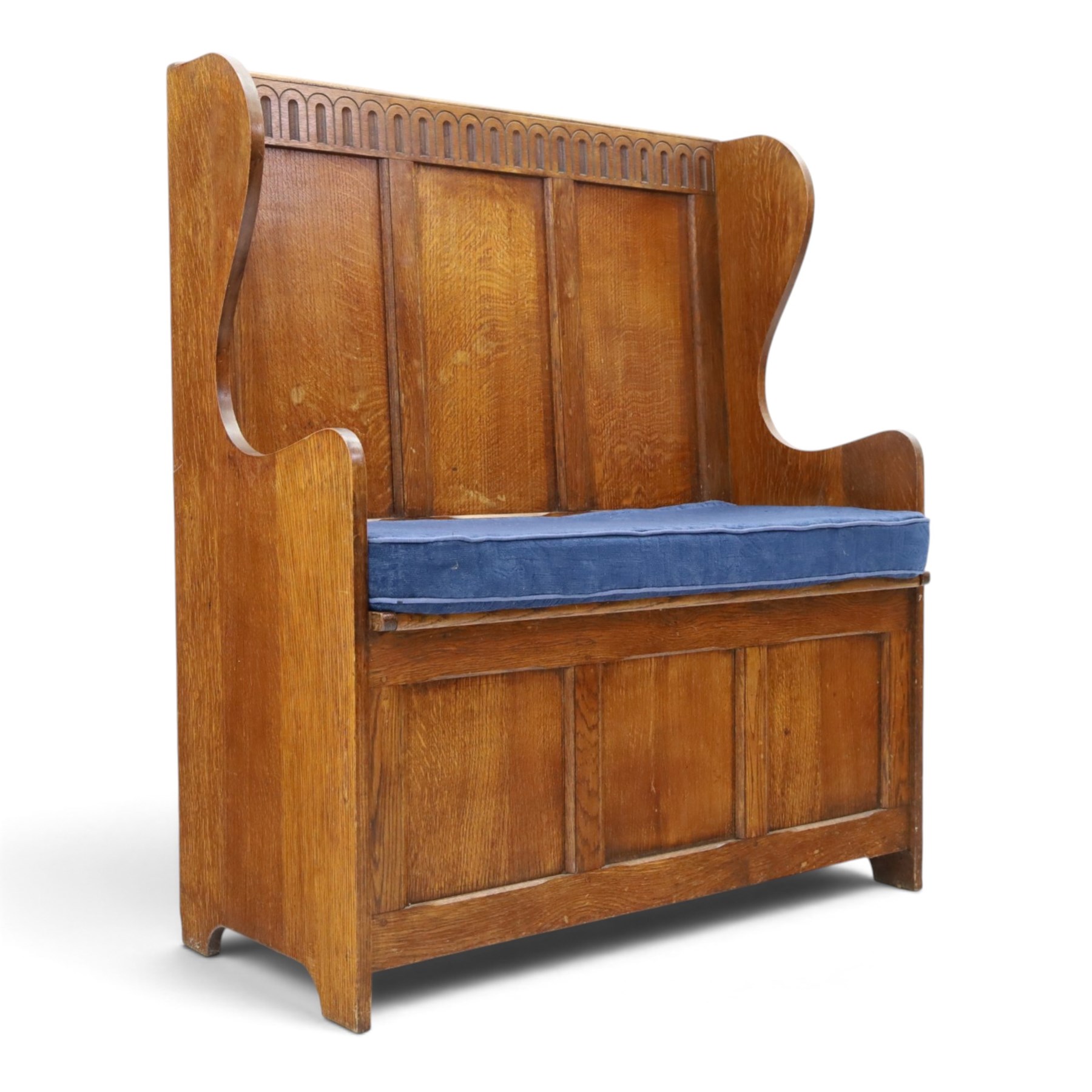 Early 20th century oak box settle, panelled back with arcaded carved rail, swept sides and arms, hinged seat with storage, panelled front