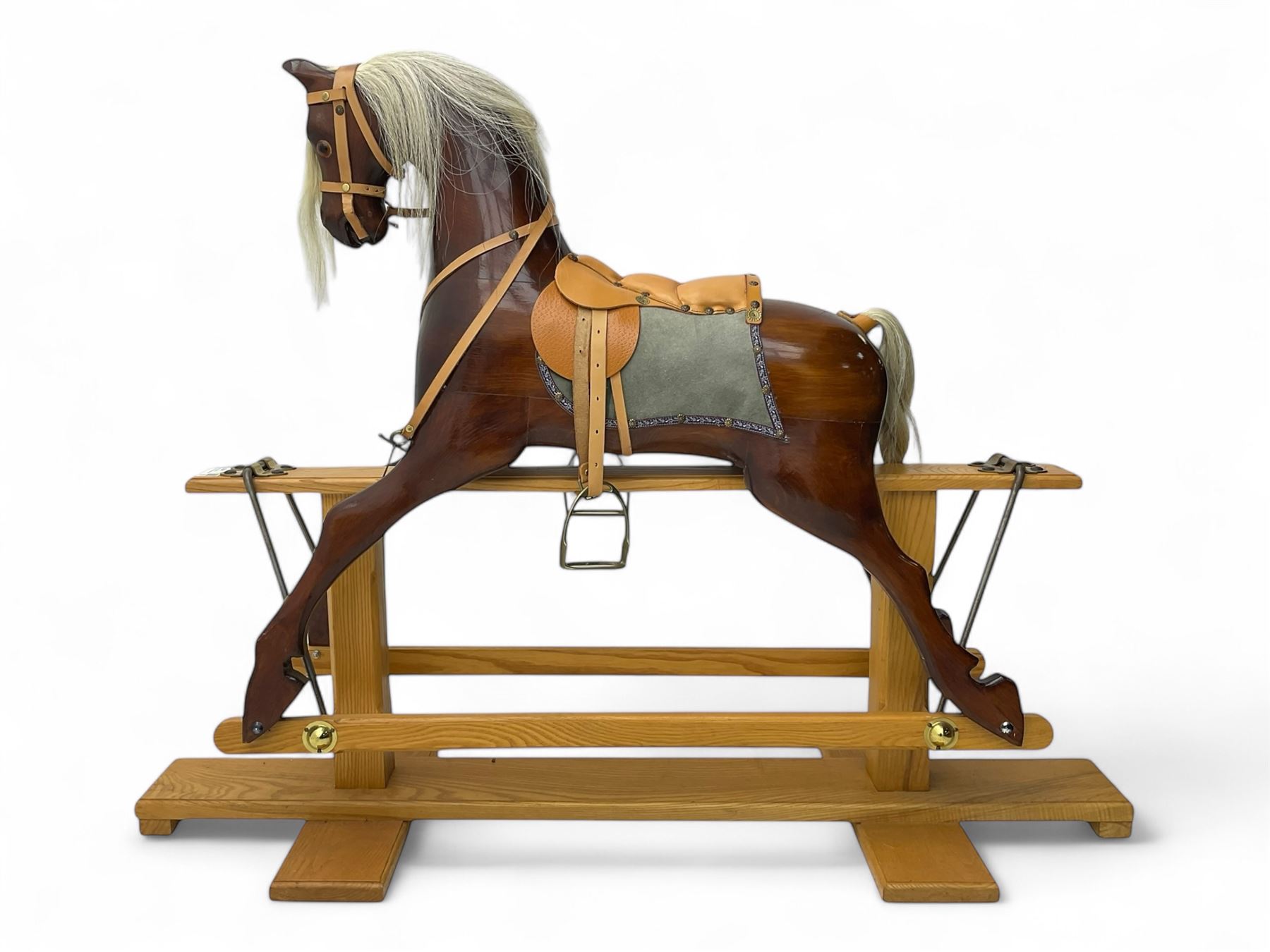 Contemporary carved wooden rocking horse, with leather saddle and bridle, horsehair mane and tail, raised on a pine stand with swing iron supports