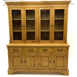 Pine Welsh dresser, projecting cornice above four glazed cupboard doors enclosing fitted shelving, base unit fitted with four short drawers above four panelled cupboards, raised on plinth base