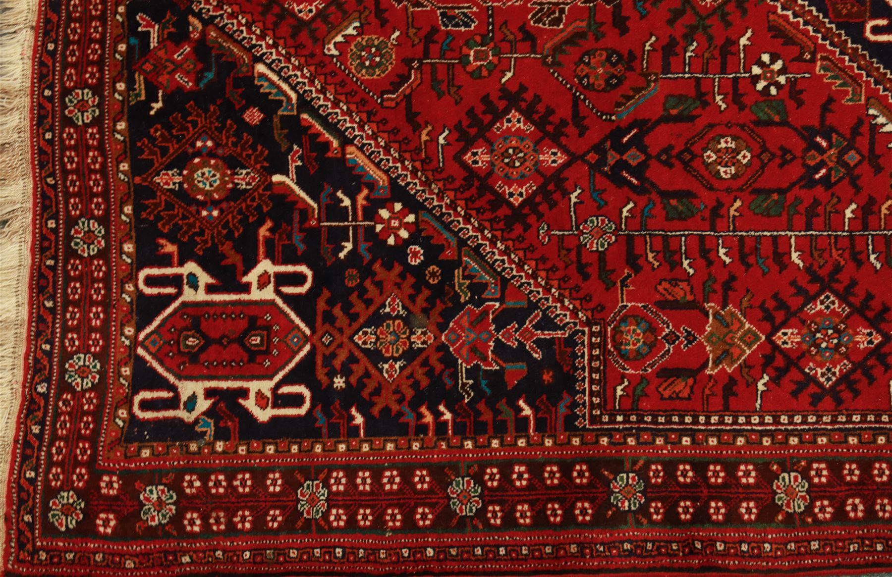 Persian tribal hand-knotted rug, crimson ground, madder field with central stepped lozenge medallion with scattered floral and geometric spandrels with rosette border 