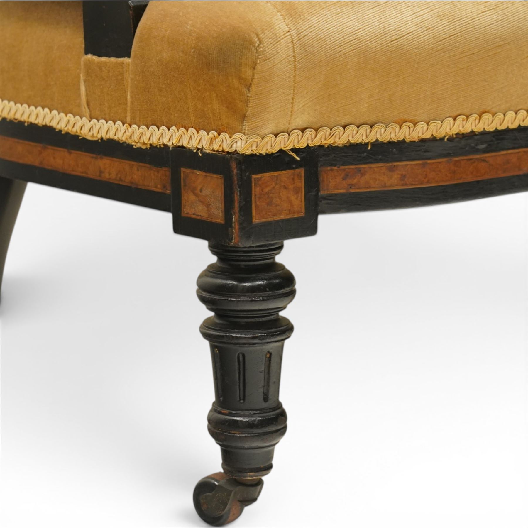Late Victorian Aesthetic Movement settee, with buttoned upholstered roll-over back and arms, open spindle gallery frame with turned uprights, stuff-over seat, on shaped ebonised supports