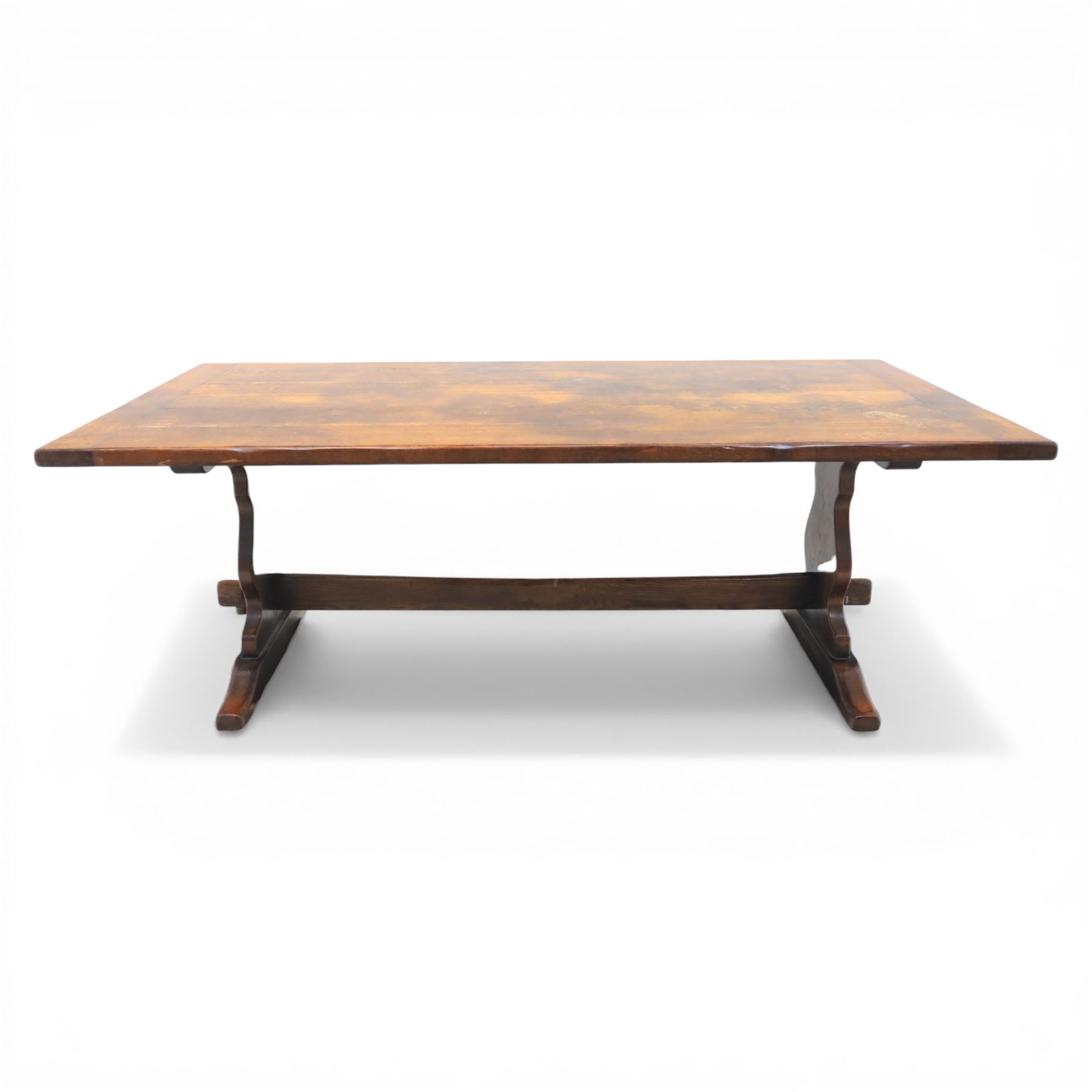 Carolean revival oak dining table and eight chairs (7+1), refectory table with rectangular boarded top and cleated ends, raised on shaped trestle end supports with central stretcher, accompanied by eight high-back chairs including a carver, leather upholstered panels and seats with studwork, on turned legs with stretchers.