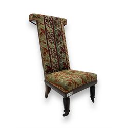 19th century mahogany framed prie-dieu chair, upholstered in red and green patterned fabric, high back with rolled top, standing on turned front supports with castors
