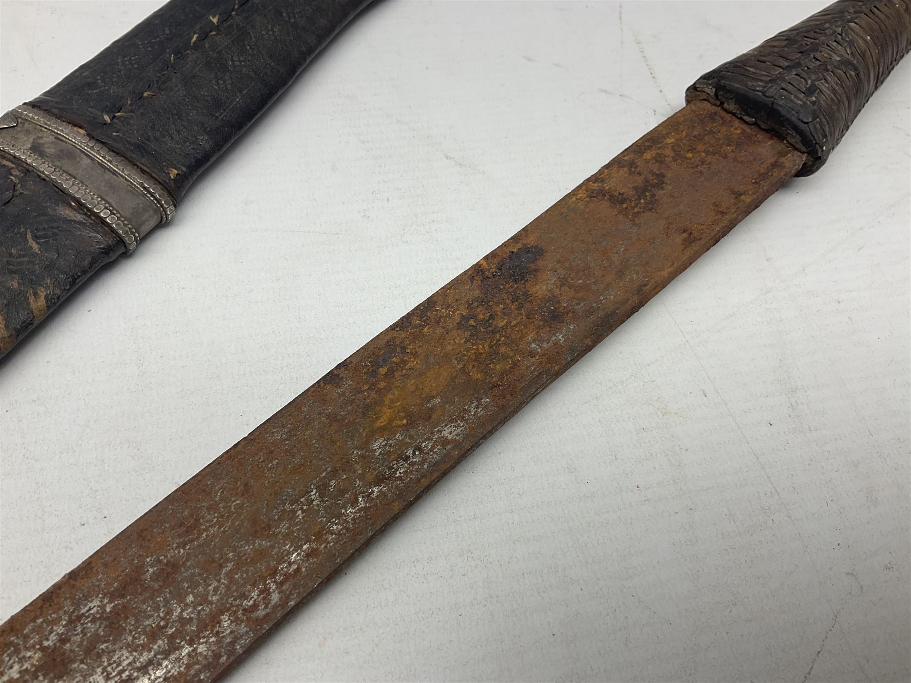 Omani presentation sword kattara, with 77cm  broad slightly curved single edge blade with two fullers, leather bound hilt woven with silver wire decoration and iron pommel;  in tooled leather scabbard with chased silver mounts and presentation plaque 'To Capt. D.M. Naylor From C Company NFR Oman Dec 1962' (Northern Frontier Regiment) L99cm overall