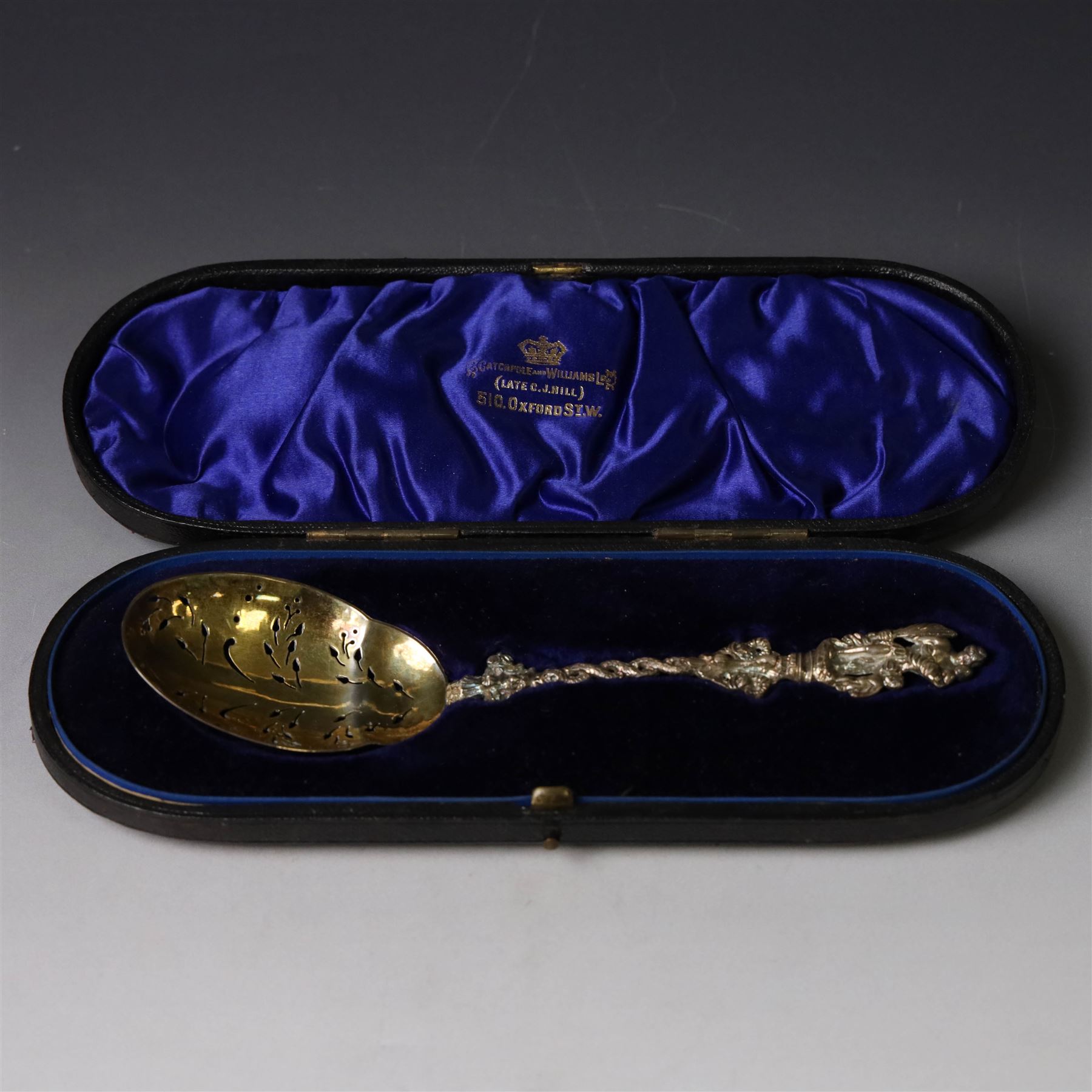 Late Victorian apostle topped sifting spoon, the finial depicting St Christopher, with entwined serpent handle and pierced gilt bowl, hallmarked Mappin & Webb, London 1890, in fitted retailers box for Catchpole and Williams Ltd