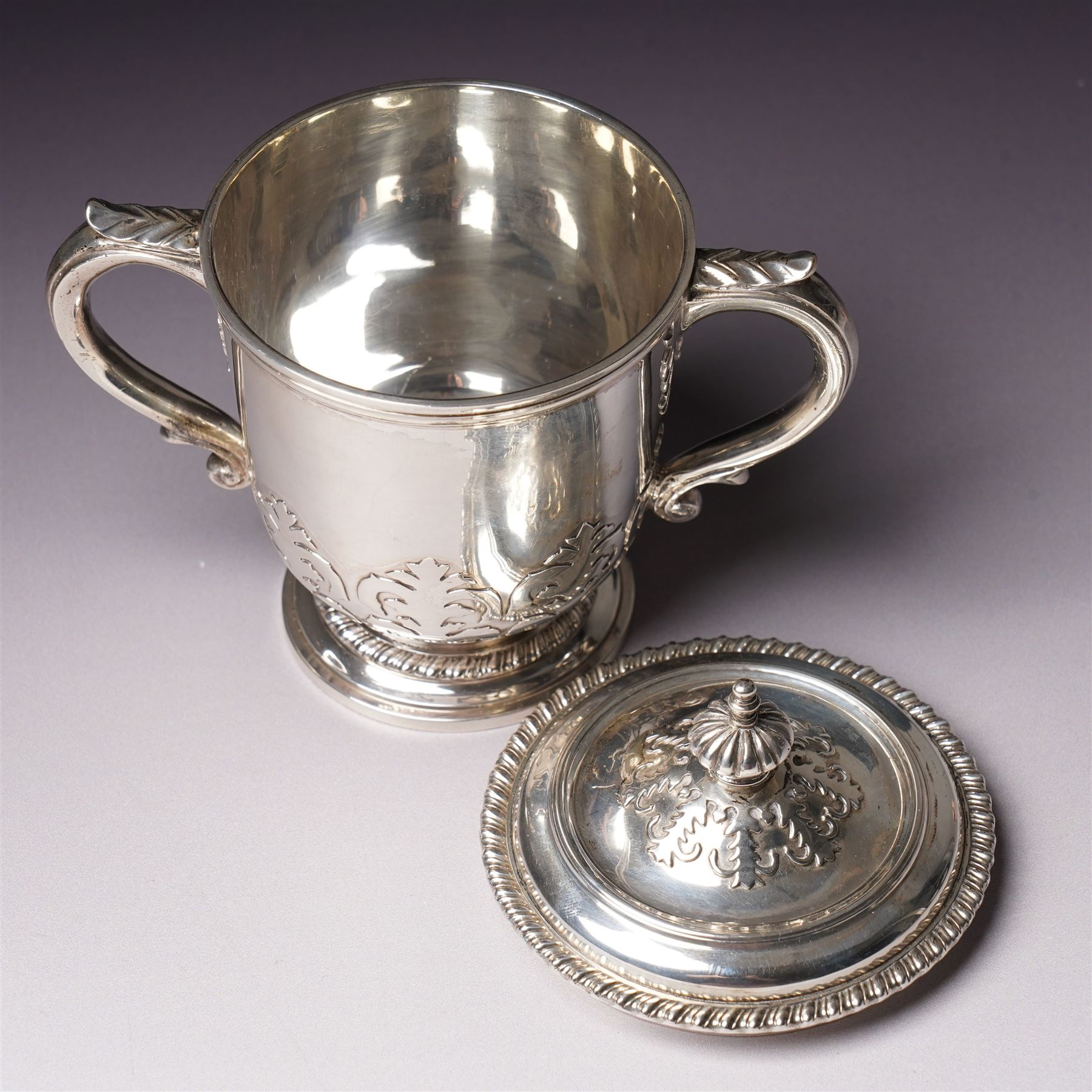 Silver two handled cup and cover with loop handles, raised stylised leaves and gadrooned edge H11cm London 1936 Maker Goldsmiths & Silversmiths Co. Ltd