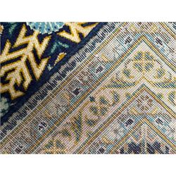 Persian indigo and pale gold ground rug, overall busy geometric design, the field decorated with hooked Hac and palmette medallions surrounded by densely patterned zig-zags and stylised foliate motifs, the border decorated with smaller Hac motifs, within multiple guard stripes 