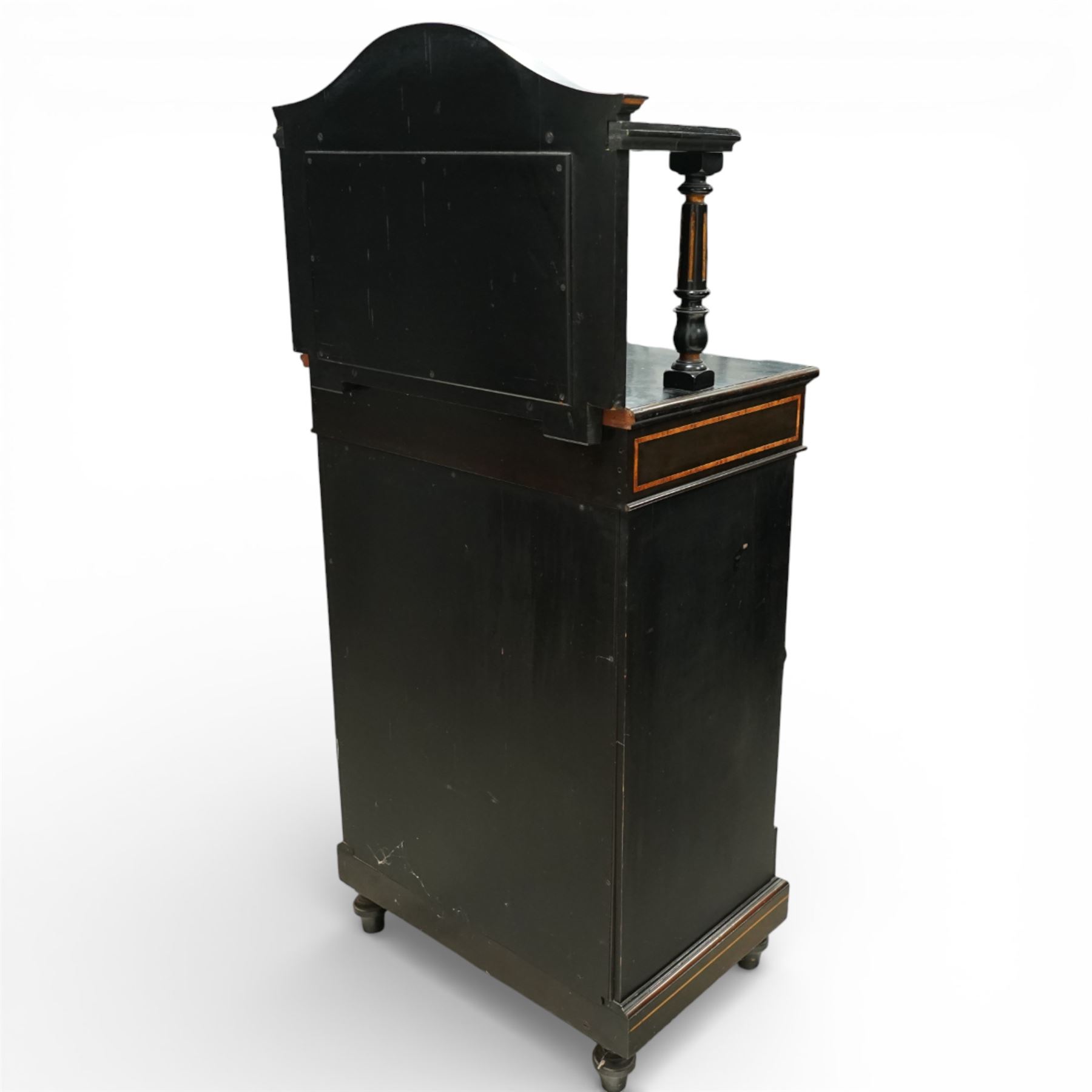 Victorian Aesthetic Movement amboyna and ebonised cabinet, the arched raised back inlaid with amboyna and floral porcelain plaque, over a raised shelf with fluted and turned supports, and a bevelled mirror plate with brass beading beneath, the inverted-breakfront top over an ornate frieze drawer with guilloche style gilt-metal mounts and porcelain plaques, the panelled door with a central porcelain plaque depicting a lady in a fuchsia gown within concentric ebonised and amboyna inlays, flanked by architectural style uprights with Corinthian capitals, raised on turned feet