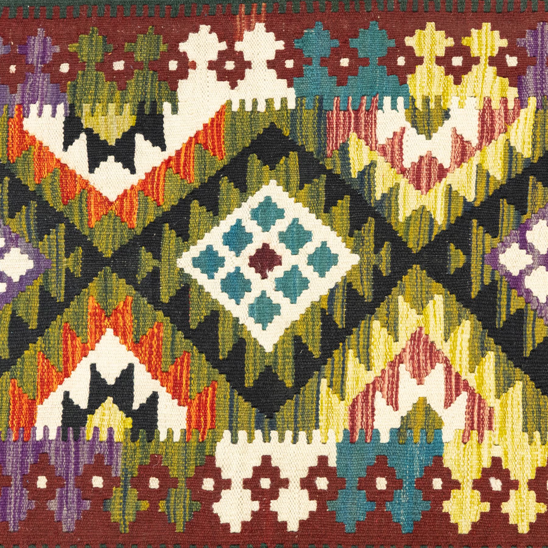 Chobi flatweave kilim runner, repeating diamond medallion design in a vibrant palette of green, red, and teal, ivory and black, within a narrow floral border