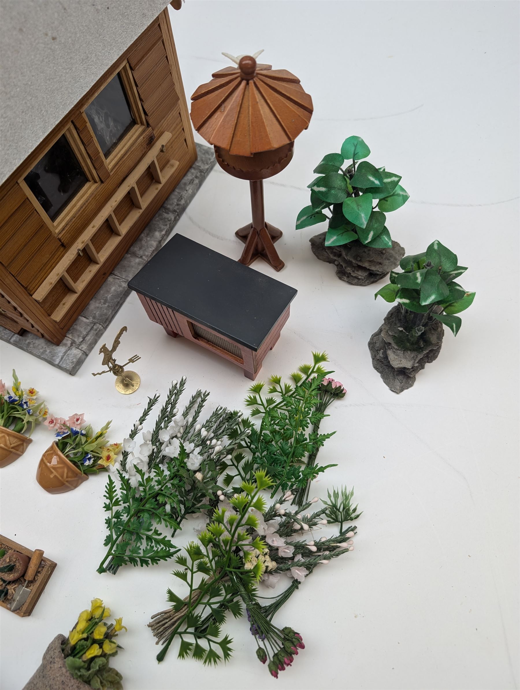 1:12 scale dolls house allotment and garden accessories, including wooden shed on a stone effect base, two vegetable patches, terracotta plant pots with flowers and foliage, stone effect plant pots, other planters, loose sunflowers, scarecrow, rabbit hutch, garden tools, fencing panels, etc 