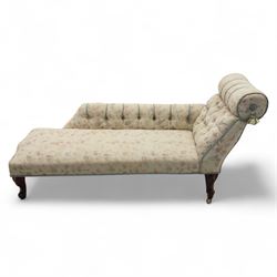 Late 19th century upholstered chaise longue, the gently scrolled headrest above a buttoned back and sprung seat, upholstered in a floral patterned fabric, raised on cabriole mahogany supports with ceramic castors