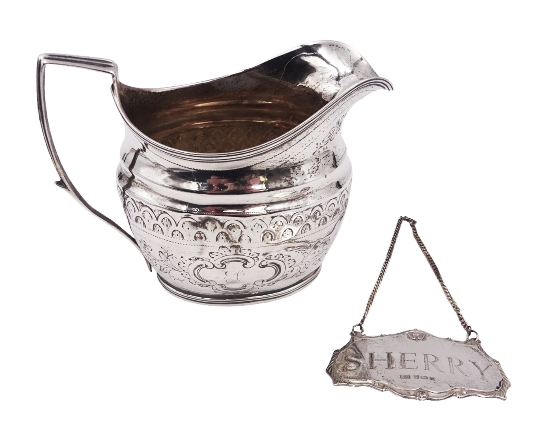 George III silver cream jug, of helmet form with angular handle, embossed with floral and scrolling decoration and engraved initial, hallmarked Edward Mayfield, London 1806, H9.3cm, together with a modern silver 'Sherry' decanter label, hallmarked Birmingham Mint, Birmingham 1986