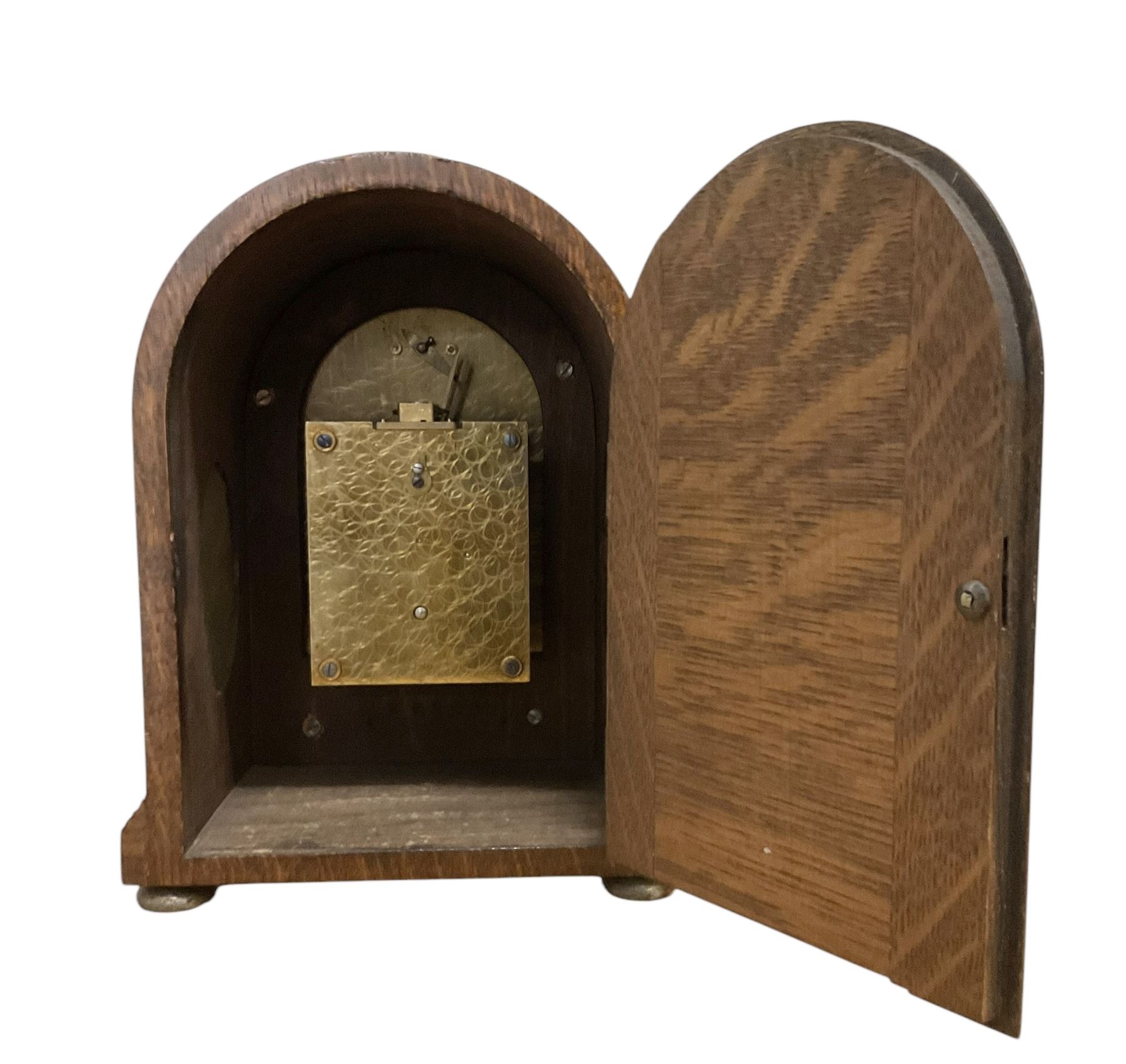 German- early 20th century oak cased 8-day mantle clock, with a round top, side frets and conforming glazed door to the dial, single sheet silvered dial with a silvered chapter and fast/slow regulation dial, Roman numerals, minute track and spade hands, going barrel movement with a lever platform escapement. With Key. 