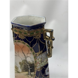 A pair of Japanese Nippon Kinjo vases, of tapering hexagonal form with twin stylised handles, the cobalt blue ground with oval hand painted panels to front and verso depicting landscapes, further detailed with smaller floral bands and panels and heightened with gilt, each with mark beneath, H30.5cm.  
