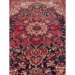 Persian Hamadan indigo and red ground carpet, large central medallion decorated with projecting palmette motifs, the surrounding field decorated with trailing branches and flower heads, crimson ground border decorated with stylised plant motifs, within floral pattern guard stripes 