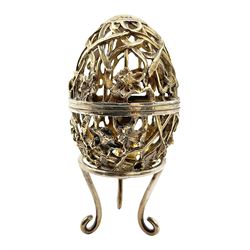 Modern silver limited edition Easter egg, no. 70/500, the gilt openwork body decorated with daffodils and detachable cover with pierced circular panel set with a single faceted blue stone, opening to reveal a gilt interior, upon silver stand with three scrolling pad feet, each hallmarked St James House Company, London 1980, height including stand 8cm