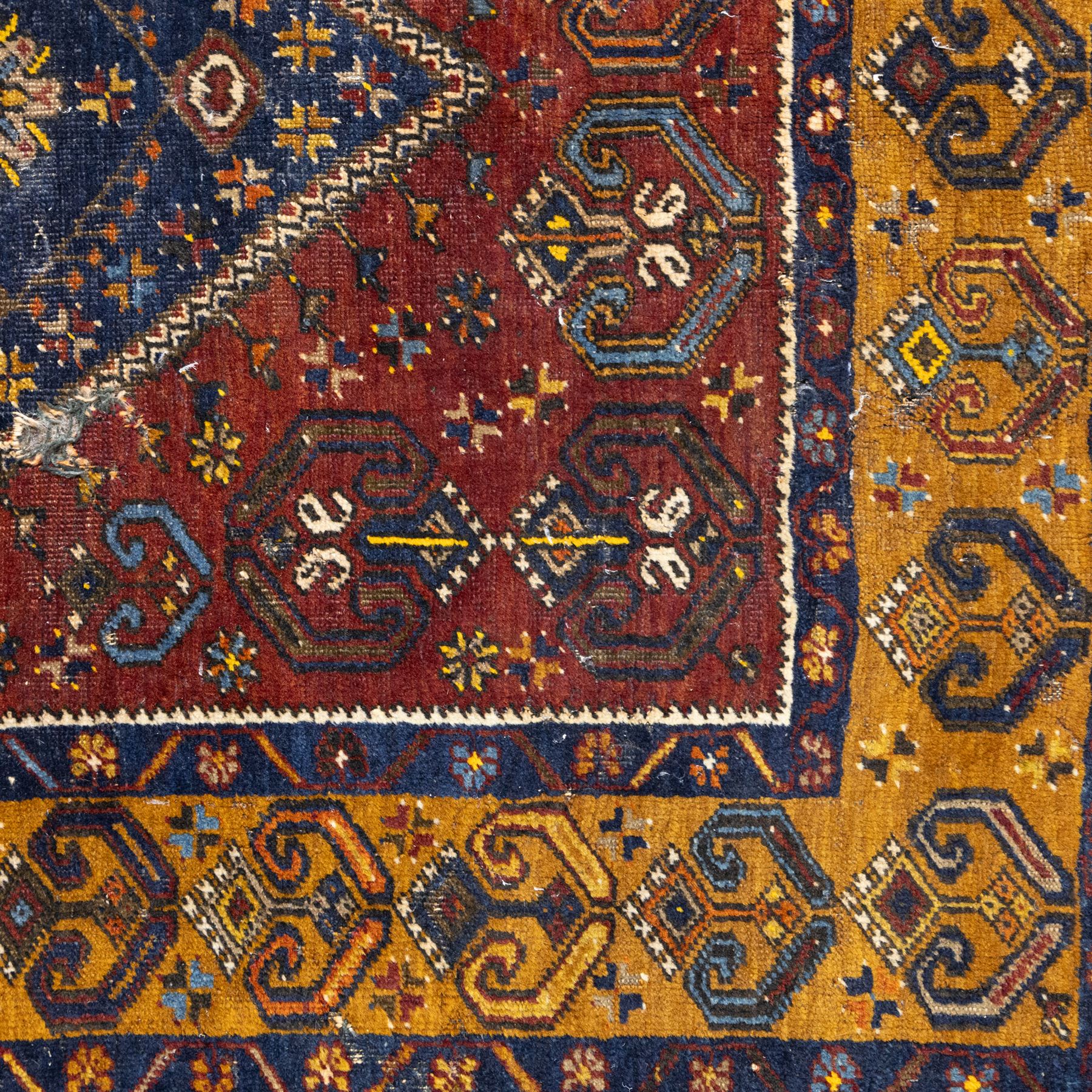Turkish Anatolian wool rug, central stepped medallion on dark blue lozenge field, red spandrels with stylised hooked motifs, ochre border decorated with repeating geometric motifs and guard stripes