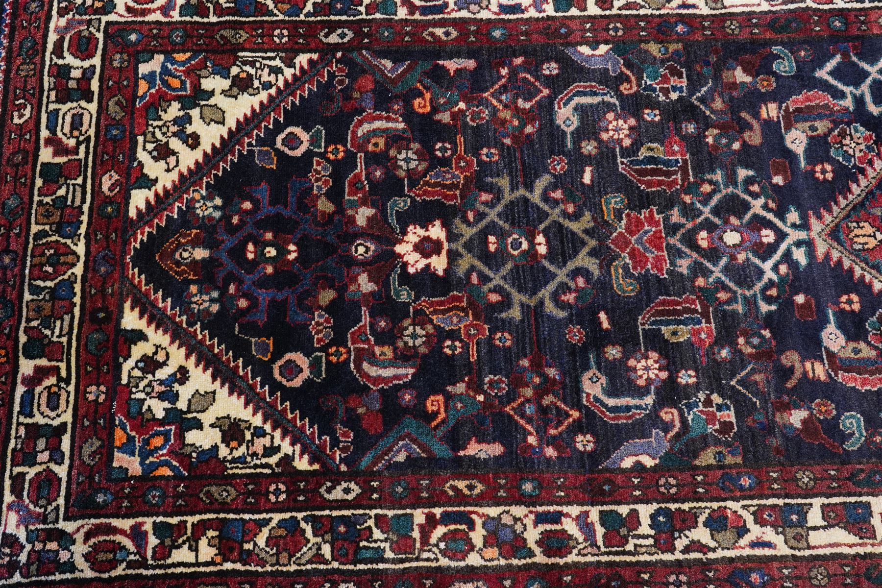 North West Persian Hamadan hand-knotted runner, indigo field with an all-over herati inspired lattice issuing from a central axis with stylized palmettes, rosettes and angular vinery, enclosed by stepped triangular spandrels with ivory reserves, broad ivory main border of stylized flowers and geometric devices, flanked by reciprocal guard stripes, cotton fringe ends 