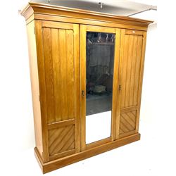 Early 20th century ash triple wardrobe projecting cornice, three doors into dim central full length mirrored door enclosing for linen slides above three drawers, platform base
