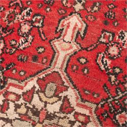 Persian crimson ground runner rug, the field decorated with repeating Herati motifs around an ivory pendant medallion, stepped ivory spandrels with stylised floral ornament, enclosed by a dark ground star border and narrow guard stripes