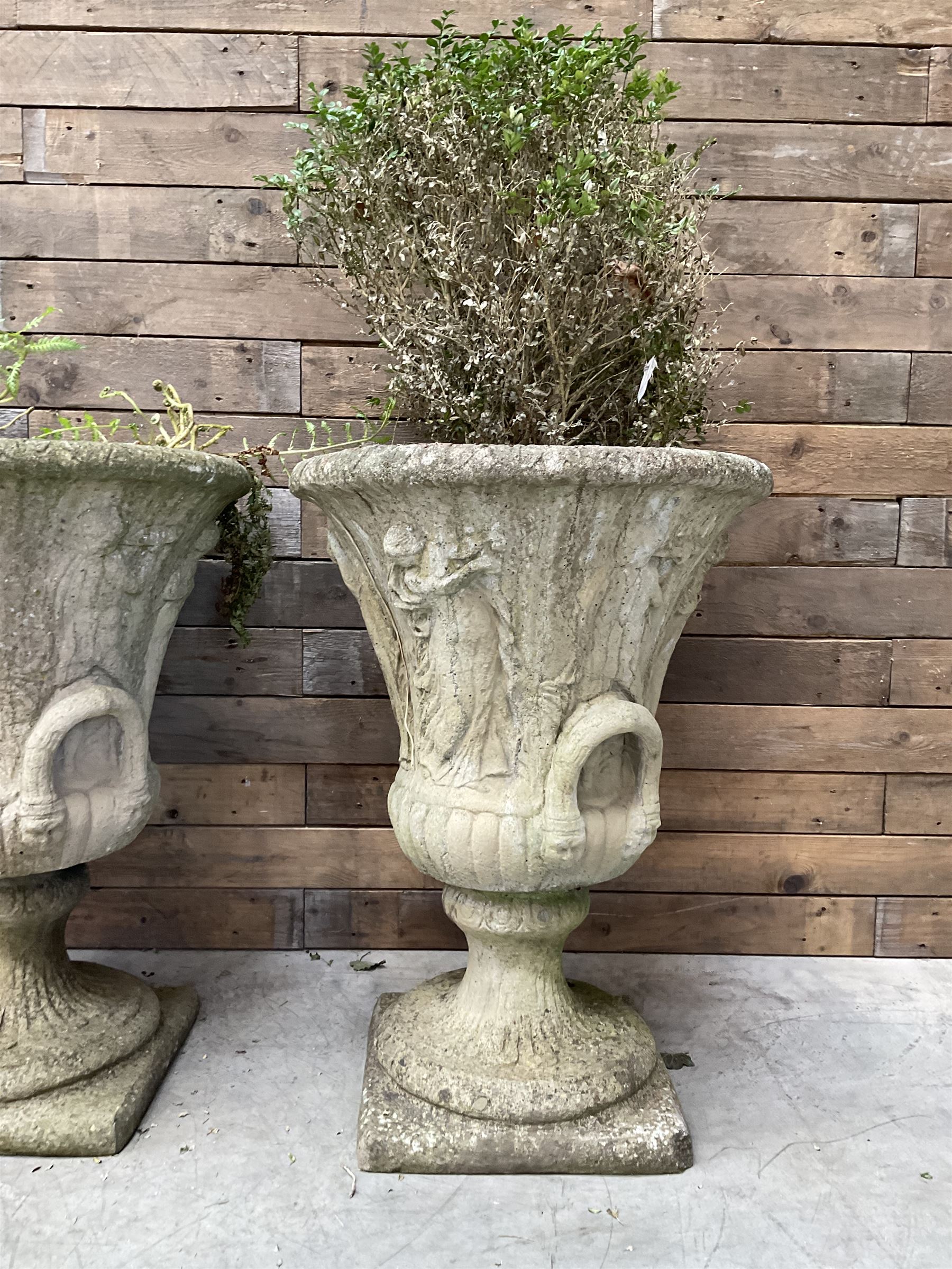 Set of four Victorian design cast stone Grecian urns, tapering form cast with figures and handles, square plinth bases