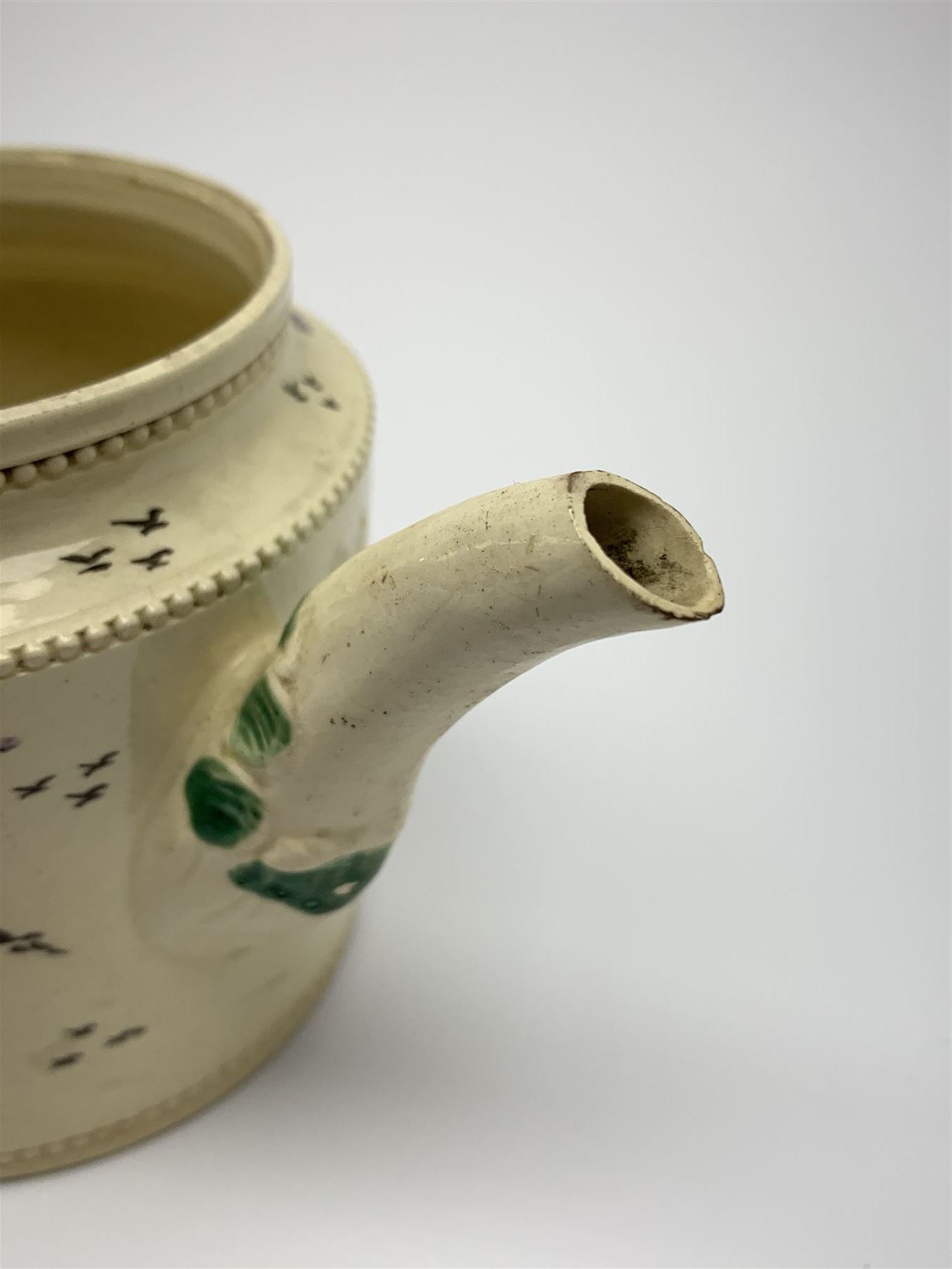 18th century creamware teapot, probably Leeds, with reeded entwined handle and floral finial to the cover, the body with hand painted polychrome decoration of figure to one side, and floral spray to the other, collectors paper label beneath inscribed Leeds Pottery, H11.5cm