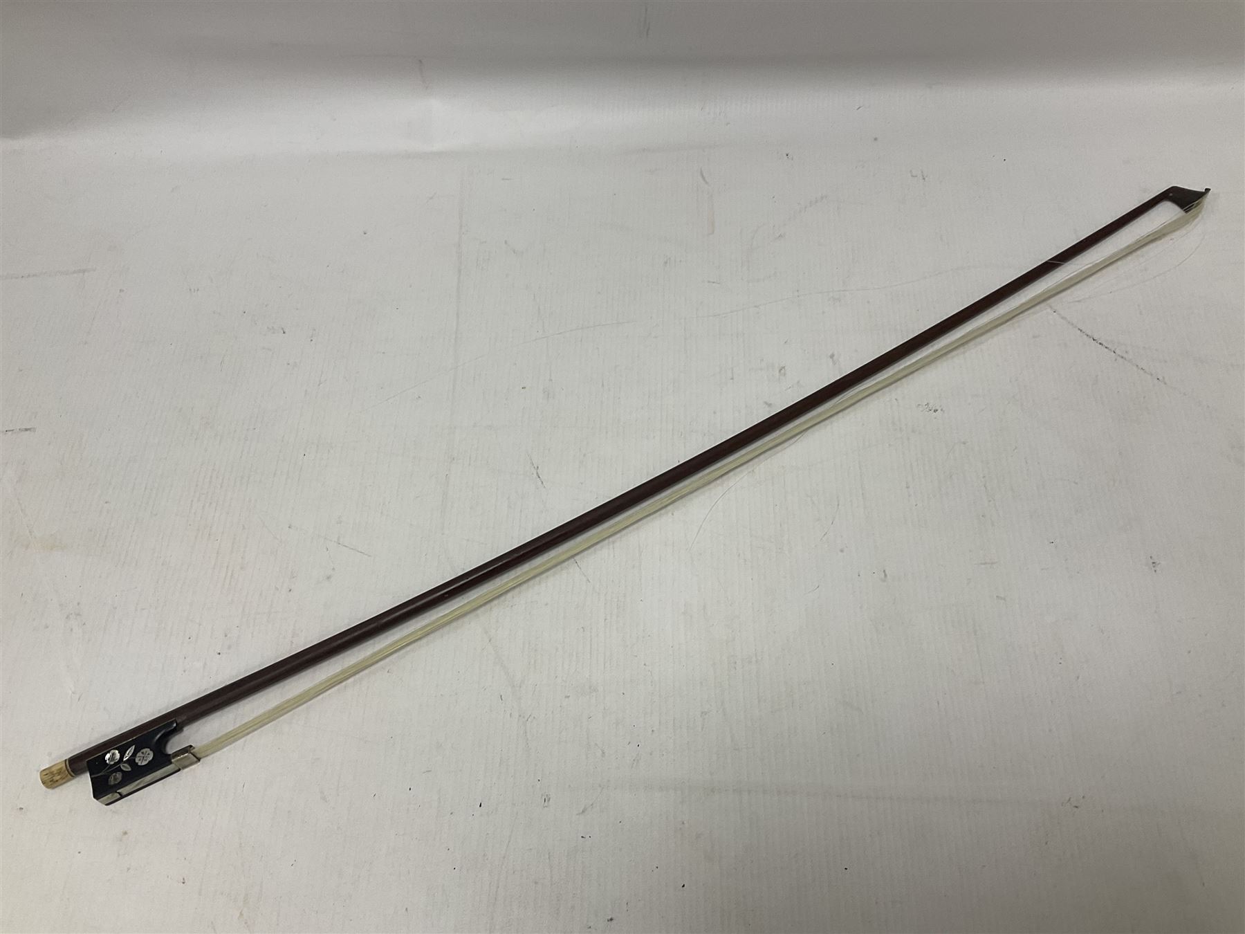 19th century wooden violin bow with a decorative mother of pearl inlay depicting flowers to the frog, with a bone adjuster screw