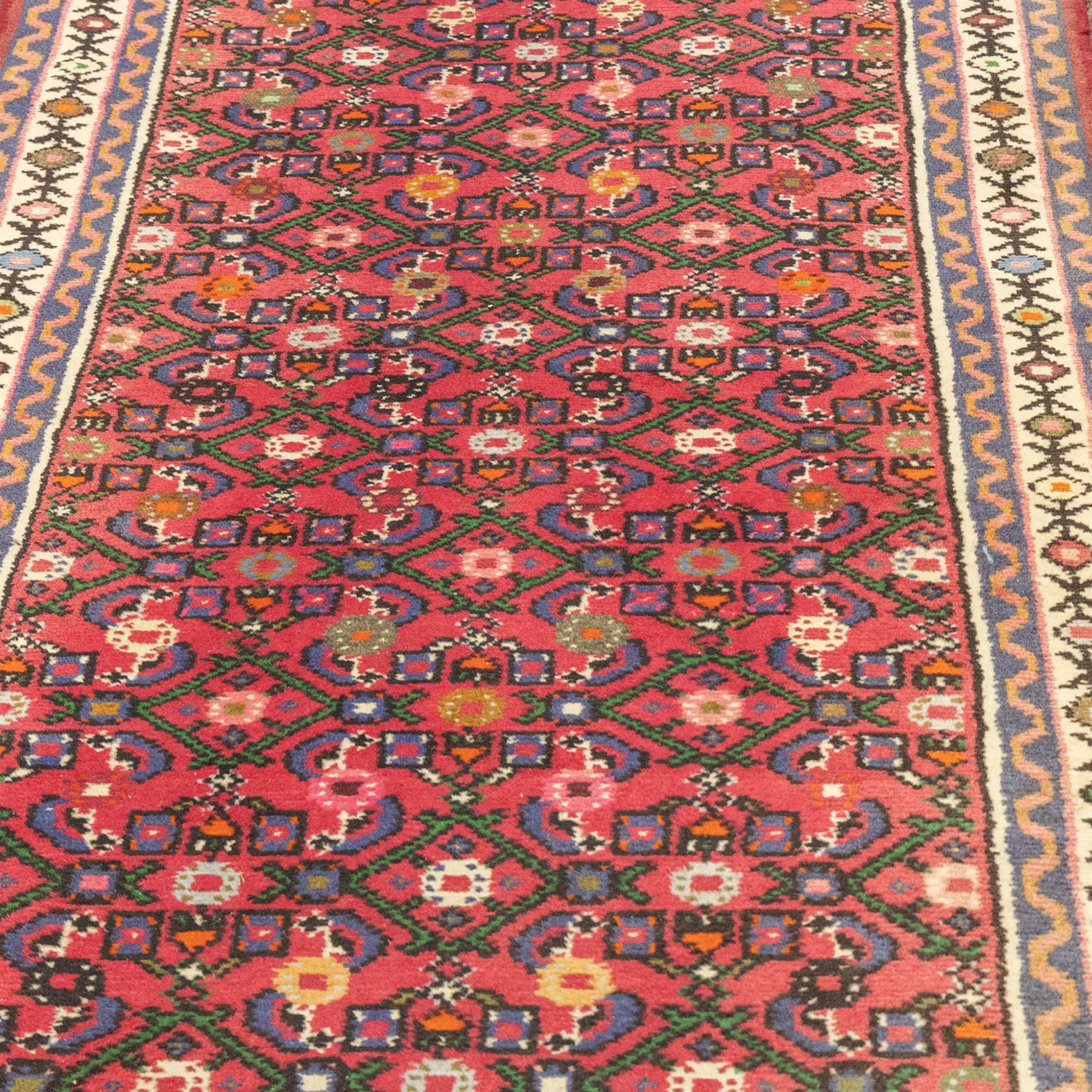 North West Persian runner, red field decorated with repeating herati motifs and small flowerheads, enclosed by cream main border with stylised floral motifs and narrow guard borders, fringed ends
