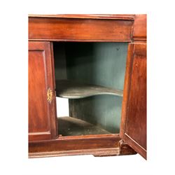 George III mahogany corner cabinet, the scrolled pediment surmounted by a brass finial and carved fretwork frieze, with fluted uprights flanking arched double doors over a painted interior fitted with shaped shelves, above a lower cupboard with twin panelled doors, on plinth base