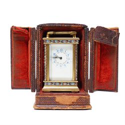 French- Edwardian miniature brass 8-day timepiece carriage clock with cloisonné panels to both base and cornice and paste gems to the front columns, decorative porcelain dial with a floral swag, blue Arabic numerals, minute track and pieced steel hands, square viewing glass to the top with a silvered lever escapement, with original leather bound traveling case.