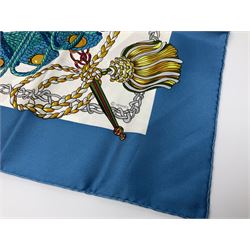 Hermès 'Le Timbalier' silk scarf, designed by Francoise Heron in 1961, printed with a central image of a gentleman on horseback donning extravagant dress, on white ground surrounded with colourful stylised knotted ropes, contained within peacock blue border, with rolled hand stitched edges and Hermes material label, 87cm square