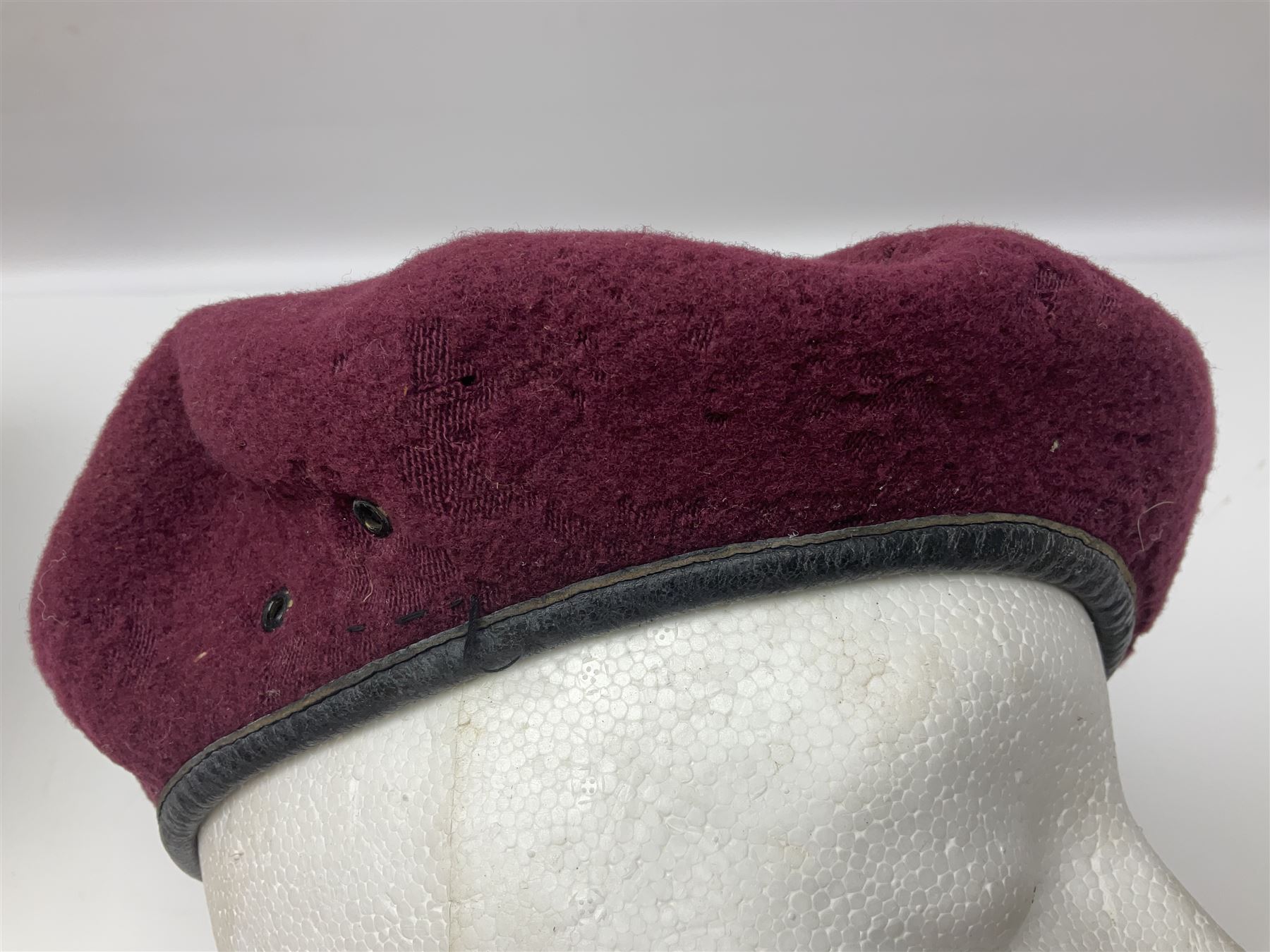 WW2 British Airborne Troops/Paratroopers Steel Helmet with green textured paint finish and netting cover, leather and sponge liner and three point chinstrap mounting; liner marked BMB 1943; together with a paratrooper's maroon beret with metal badge (2)