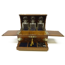 Edwardian oak three bottle tantalus with silver-plated mounts, carved floral panels, twin lidded front enclosing a four sectioned compartment above a secret drawer containing cribbage board, H32.5 x W36cm x D26.5cm   