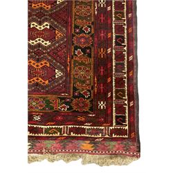 Persian maroon ground rug, the field decorated with interconnected lozenges, geometric design border decorated with stylised plant motifs